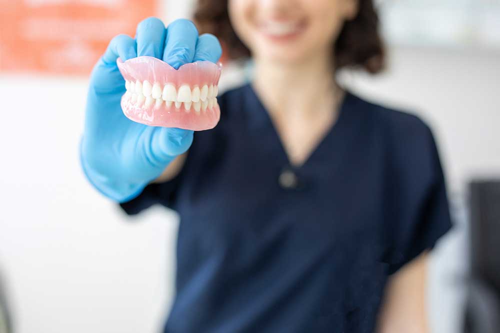 close up of dentures, held by a female dental professional